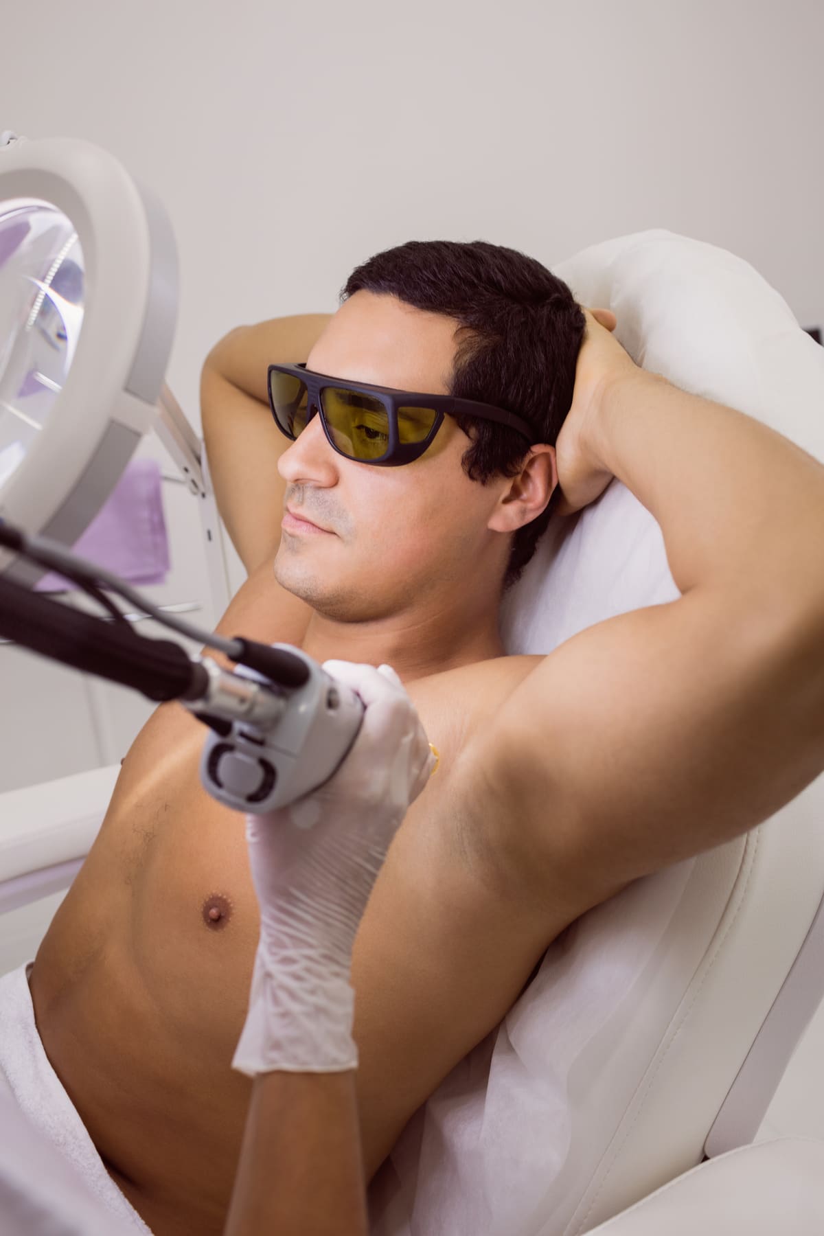 Laserontharing van de oksels bij een man met een beschermbril