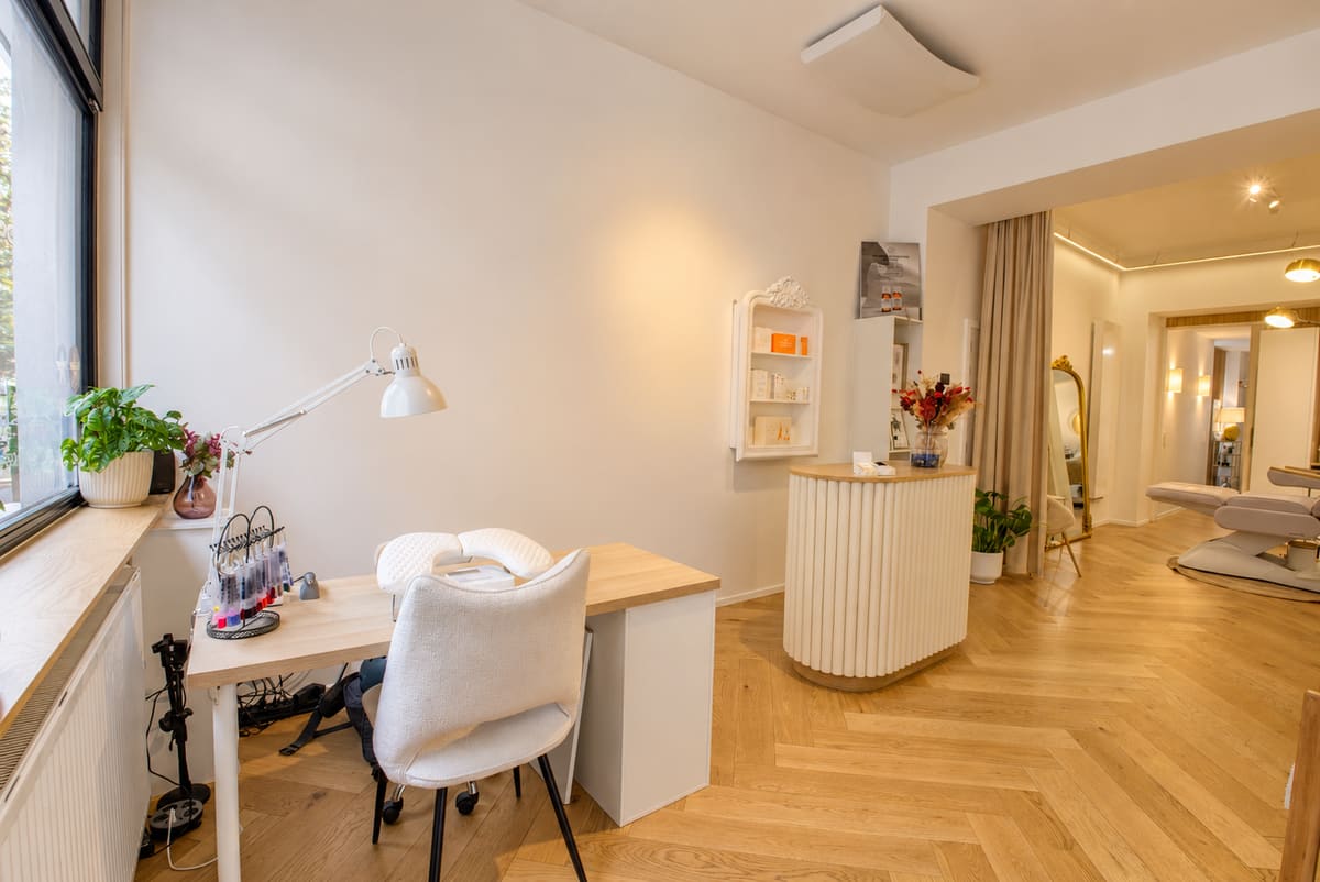 Poste de beauté des ongles près de la fenêtre, avec la cabine de soins en arrière-plan