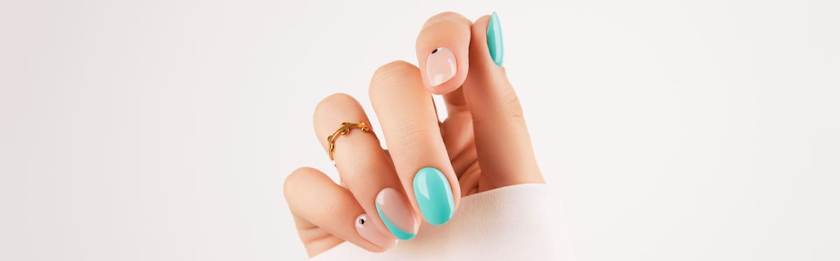Hand with turquoise and pink painted nails after a manicure