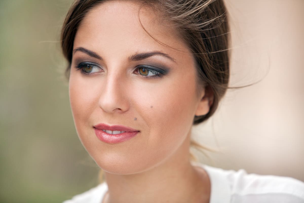 Portrait of a smiling woman with a beauty mark on her face