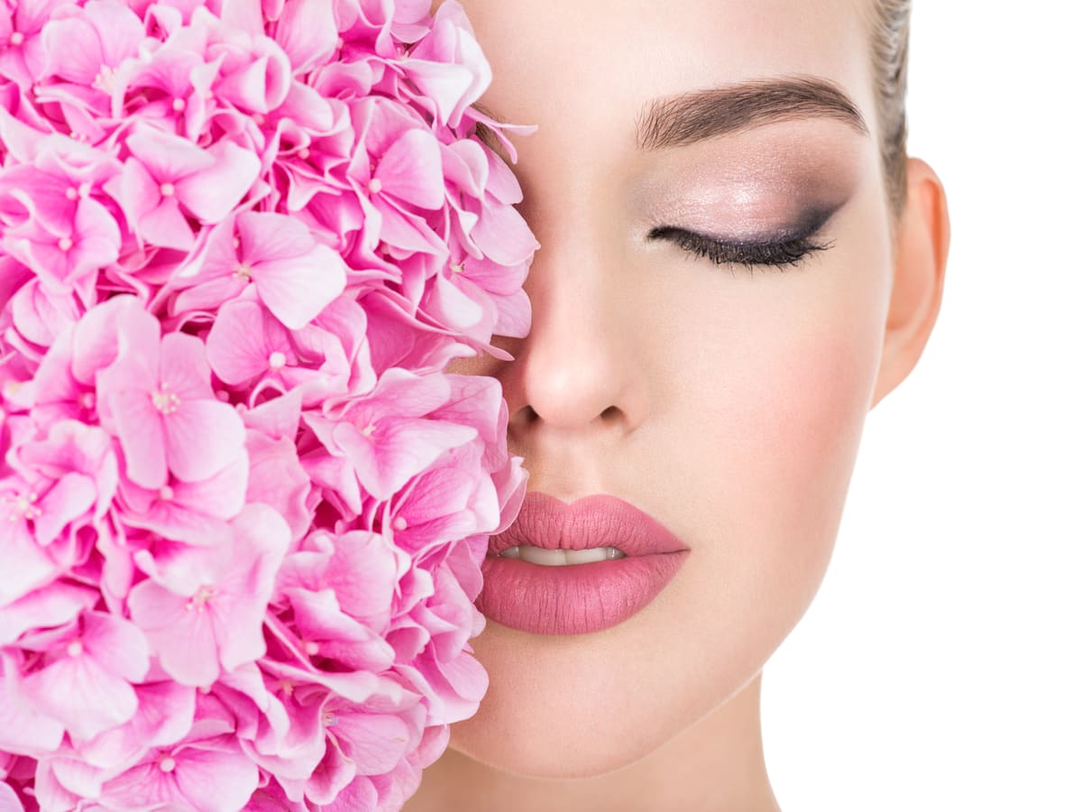 Stralende bruidsmake-up in roze tinten, naast een boeket hortensia's