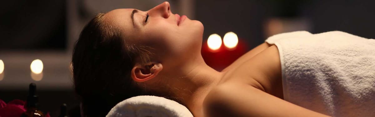 Liggende vrouw geniet van een ontspannende massage in gedempt licht