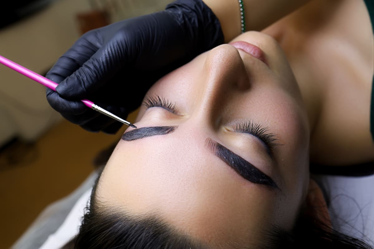 Henna wordt met een kwastje op de wenkbrauwen aangebracht tijdens een Henna Brows-behandeling
