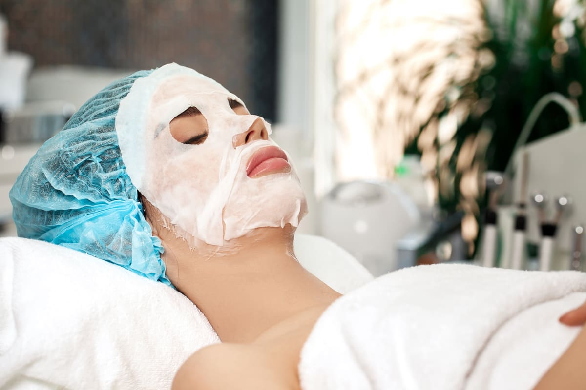 Cliente allongée avec un masque appliqué sur le visage pendant un soin purifiant
